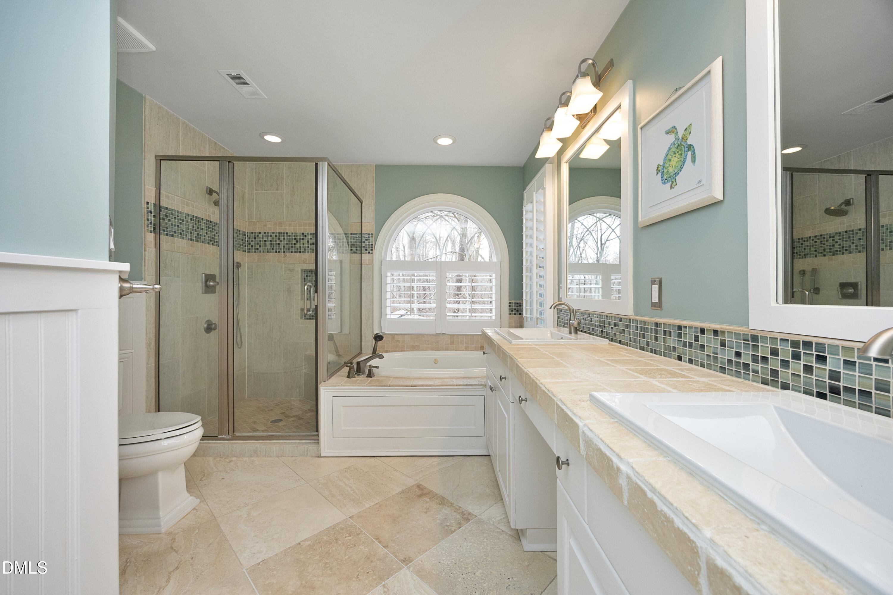 10728 Winding Wood Trail Raleigh, NC 27613 - Photo 21 of 54 a spacious bathroom with a bathtub shower sink mirror vanity and a toilet