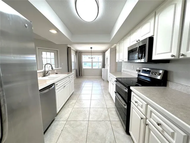 a large kitchen with stainless steel appliances granite countertop a stove a sink dishwasher and a microwave oven with white cabinets