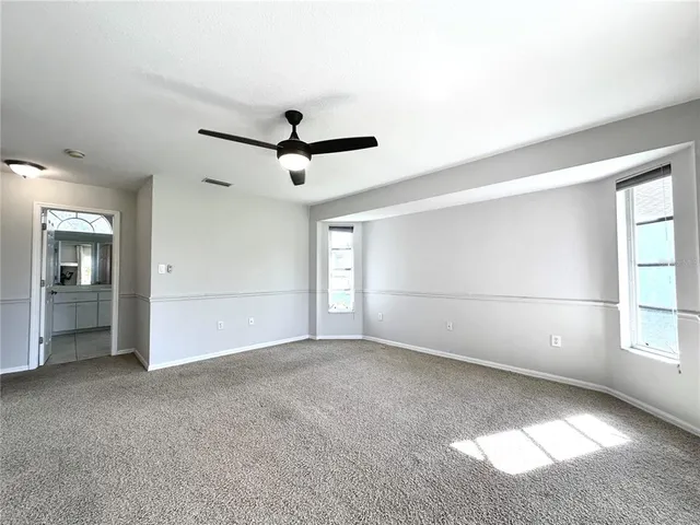 an empty room with windows and fan