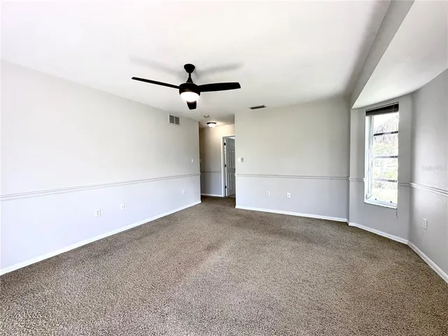 an empty room with windows and fan