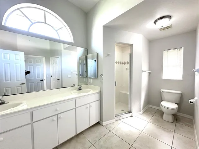 a spacious bathroom with a double vanity sink toilet and a mirror
