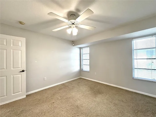 an empty room with windows and fan