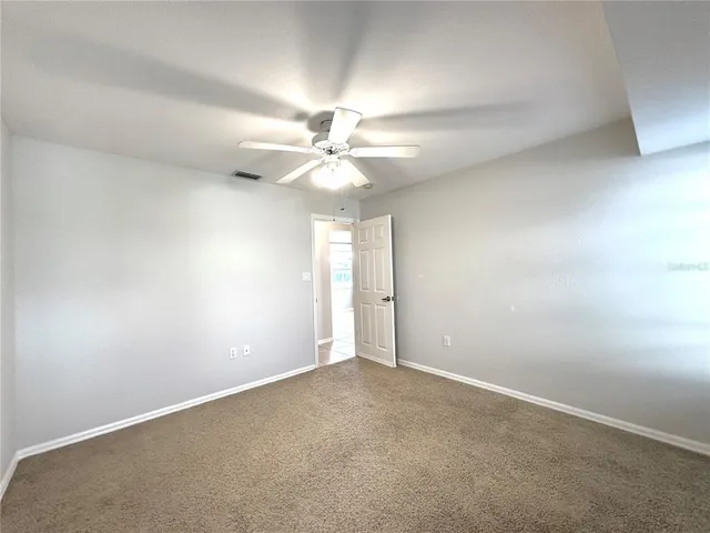 an empty room with a chandelier fan and windows