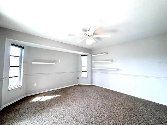 an empty room with windows and ceiling fan