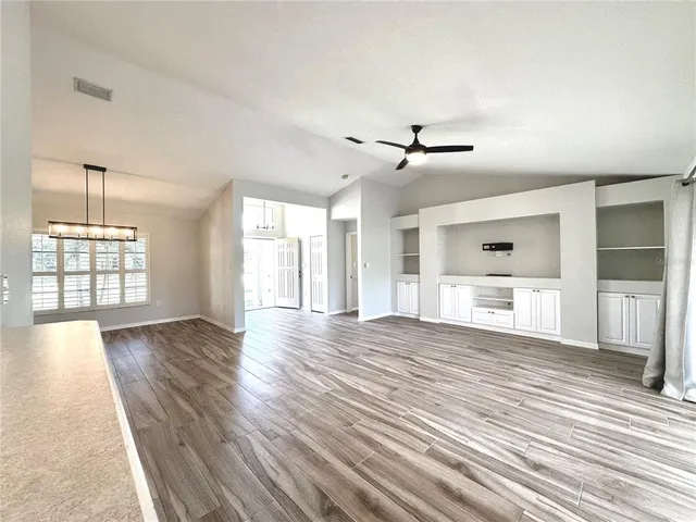 a view of an empty room with a window and wooden floor