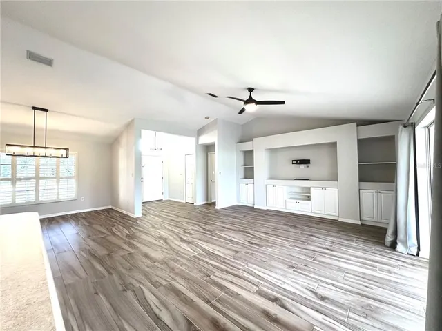 a view of an empty room with window and wooden floor