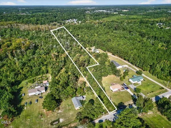 an aerial view of residential houses with outdoor space and trees all around