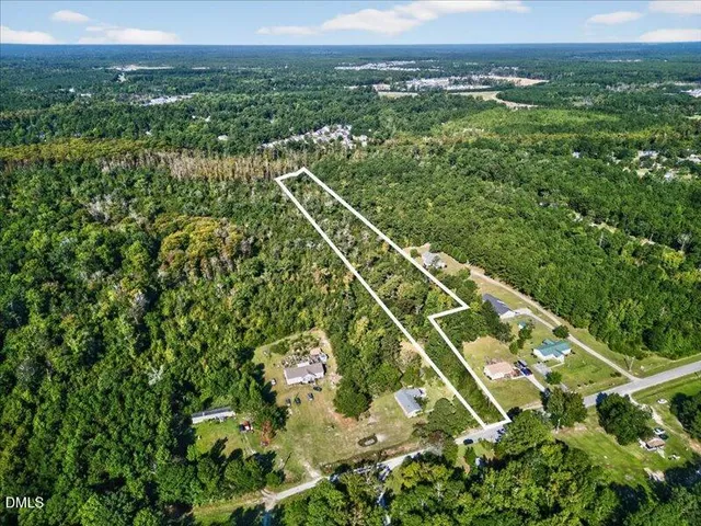 an aerial view of residential houses with outdoor space and trees