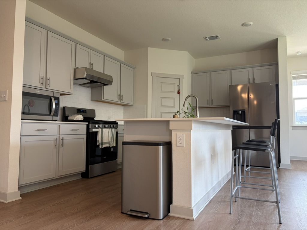 10708 Gonzales Ranger Pass Austin, TX 78754 - Photo 24 of 40 A contemporary kitchen offers sleek cabinetry, an island with seating, and durable wood-look flooring.