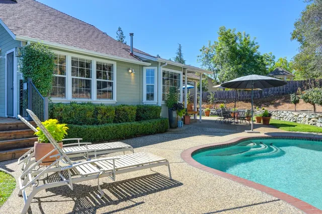 a view of a house with a backyard patio and swimming pool