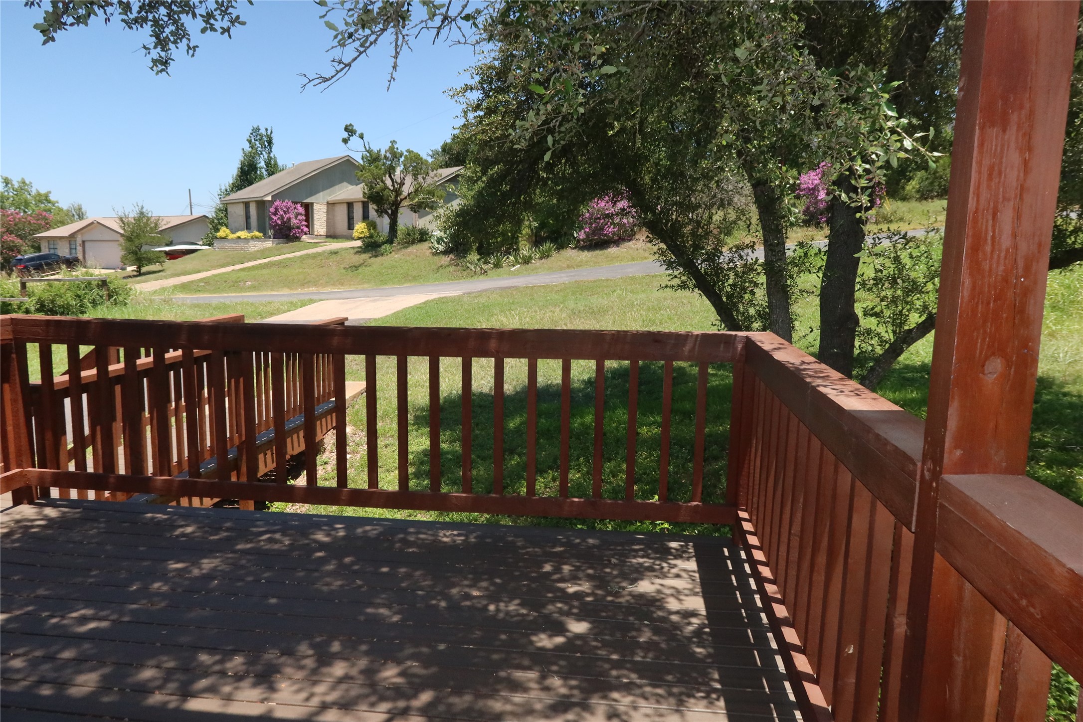Shaded wooden stairs lead down from an elevated vantage overlooking mature native trees.
