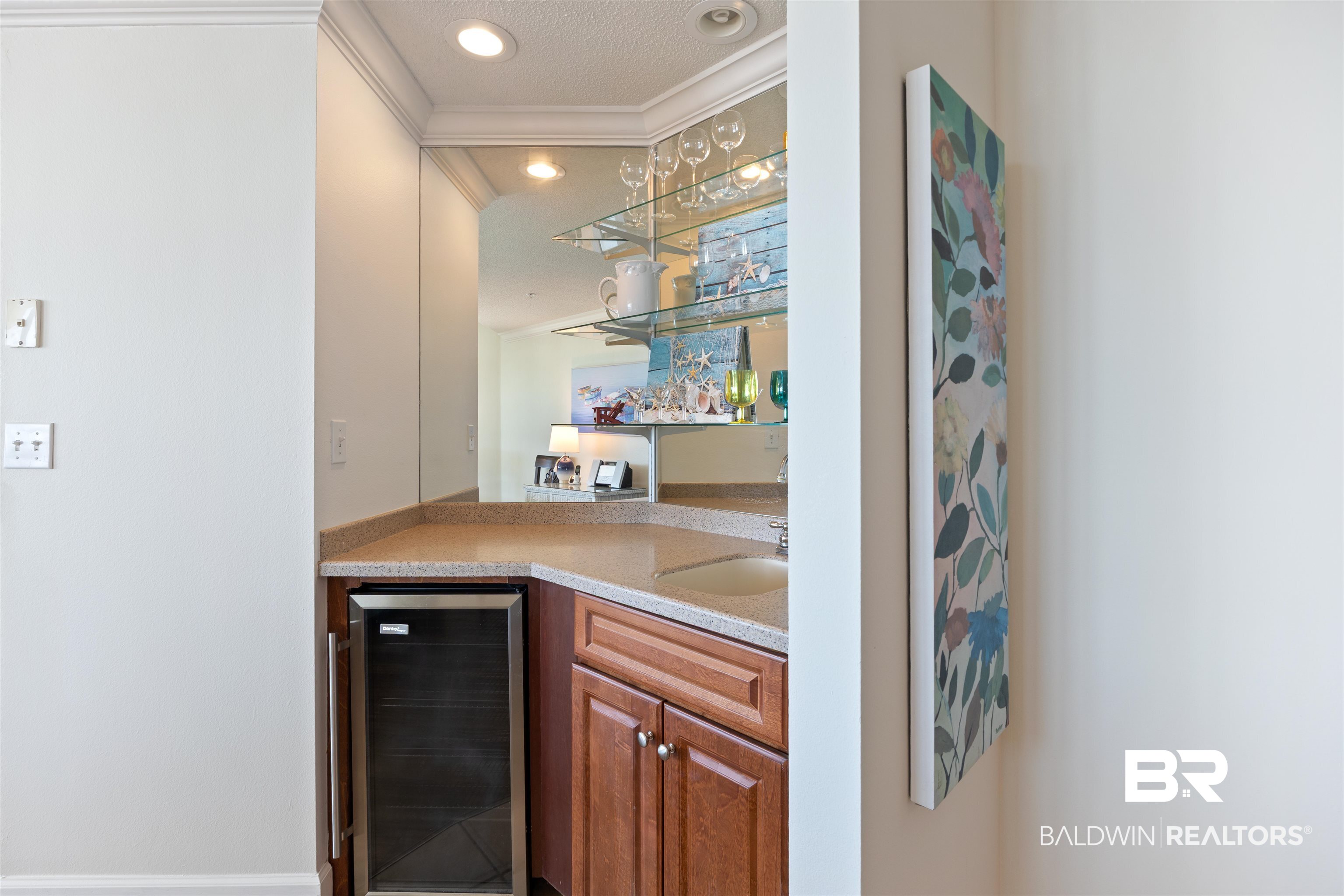 27580 Canal Road, Unit 1431 Orange Beach, AL 36561 - Photo 30 of 73 Indoor wet bar with beverage cooler, crown molding, light stone countertops, open shelves, and brown cabinetry