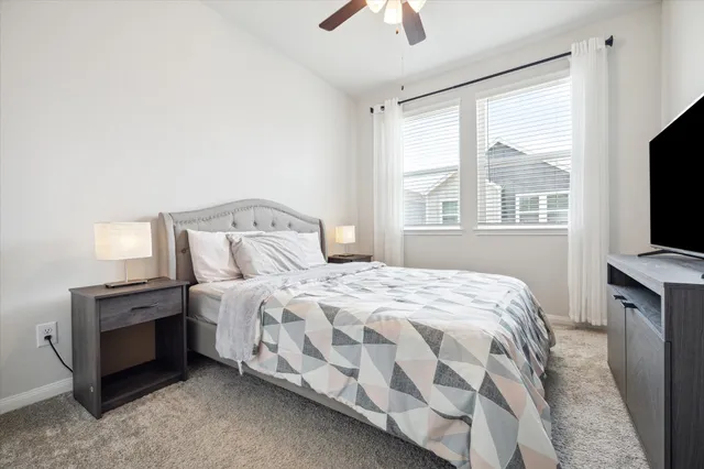 a bedroom with a bed and a flat tv screen on dresser