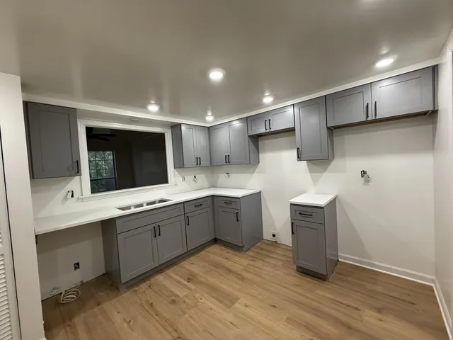 a large kitchen with a sink and dishwasher a oven with wooden floor