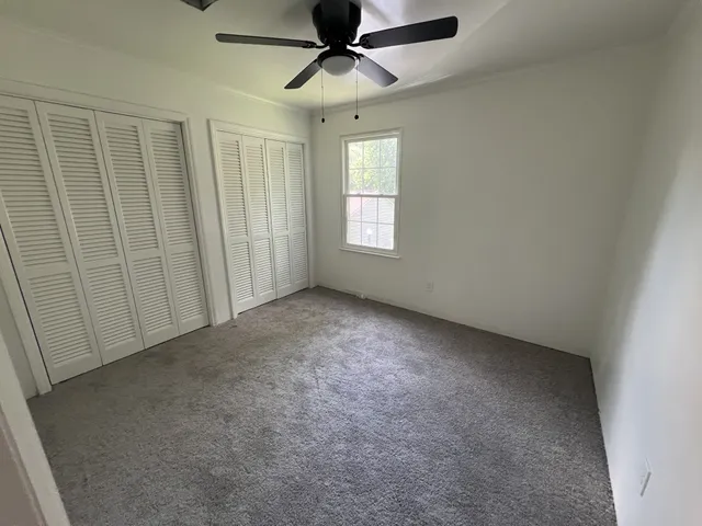 an empty room with windows and fan