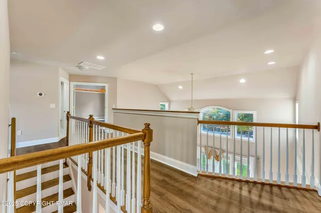 an empty room with wooden floor fireplace and windows