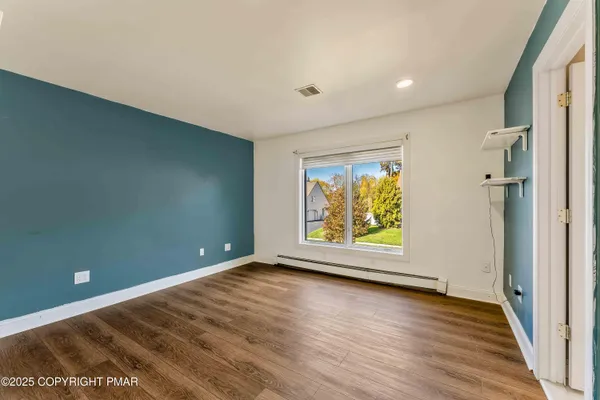 a view of an empty room with wooden floor and a window
