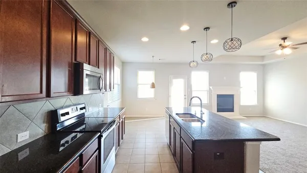 a kitchen with stainless steel appliances granite countertop a sink a stove and a wooden floors