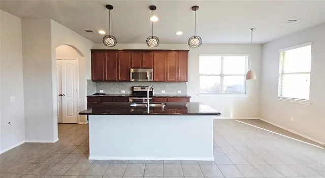 a kitchen with kitchen island granite countertop a sink window and cabinets