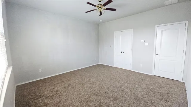 an empty room with a ceiling fan and window