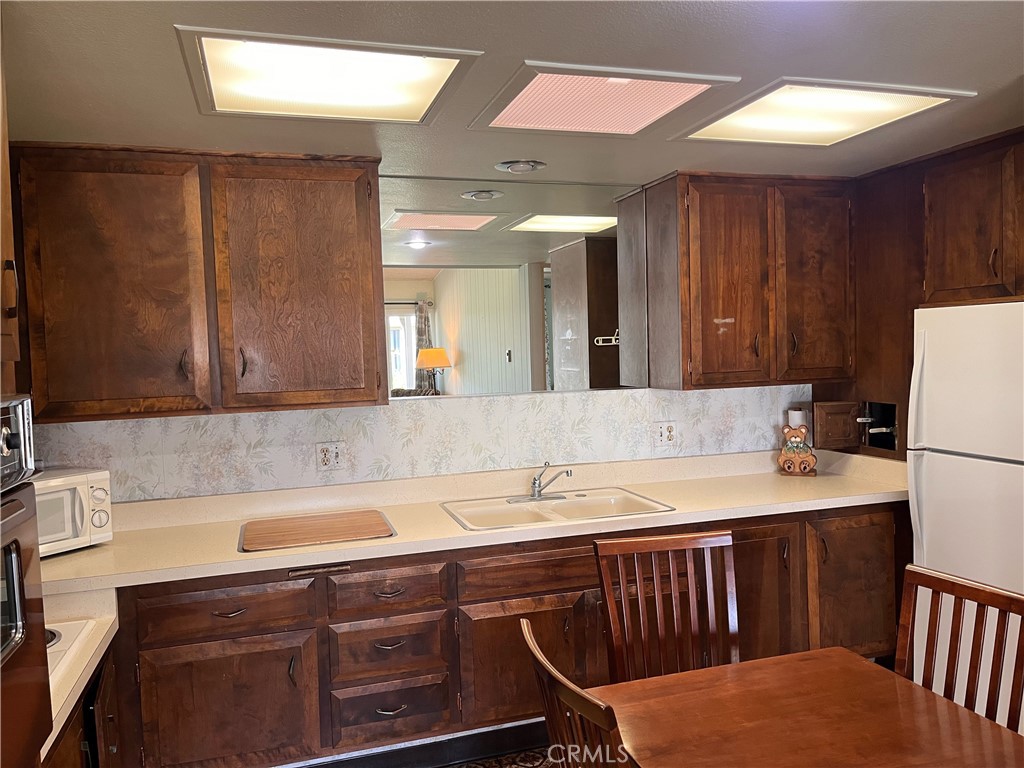 1075 Brookline Road Seal Beach, CA 90740 - Photo 11 of 13 a kitchen with a sink a refrigerator and wooden cabinets