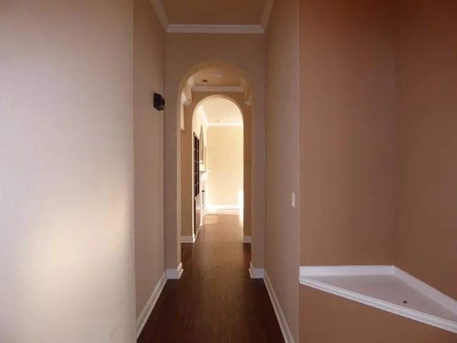 a view of a hallway with wooden floor and a bathtub