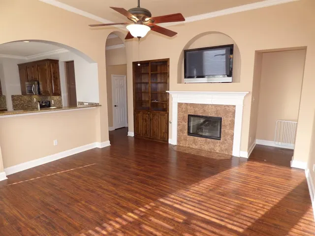 a view of a livingroom with a fireplace a ceiling fan and wooden floor