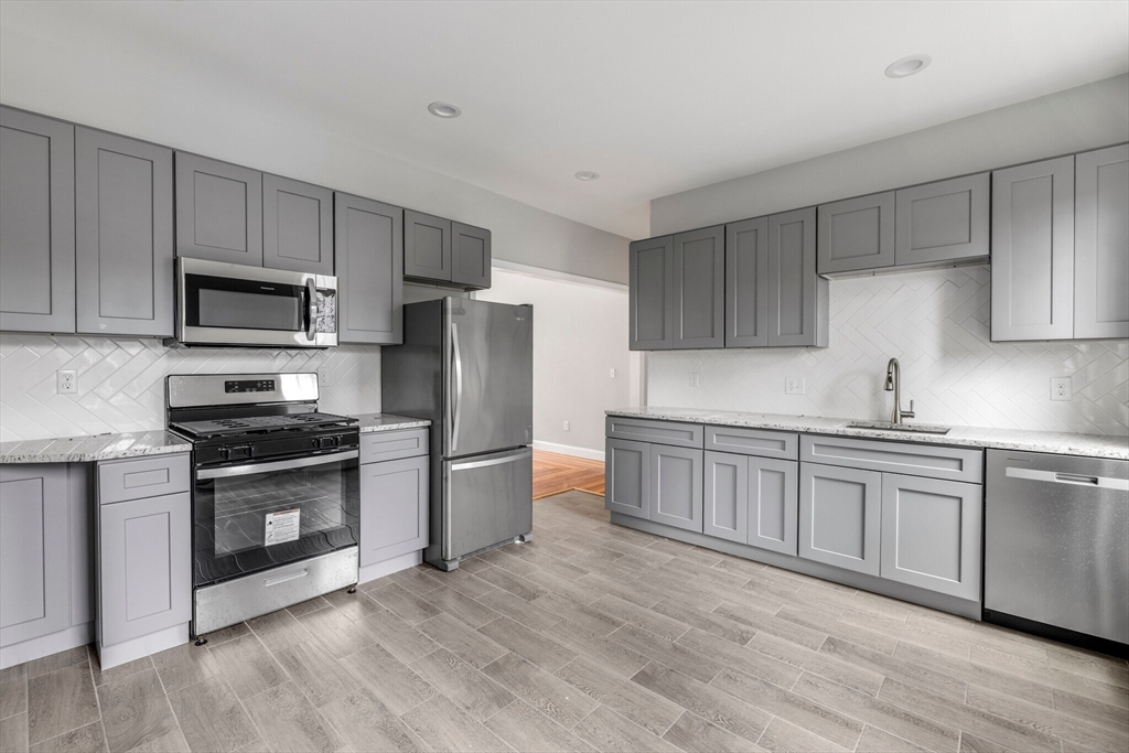 33 Wolcott Street, Unit 3 Boston, MA 02121 - Photo 2 of 8 a kitchen with a refrigerator stove and wooden cabinets
