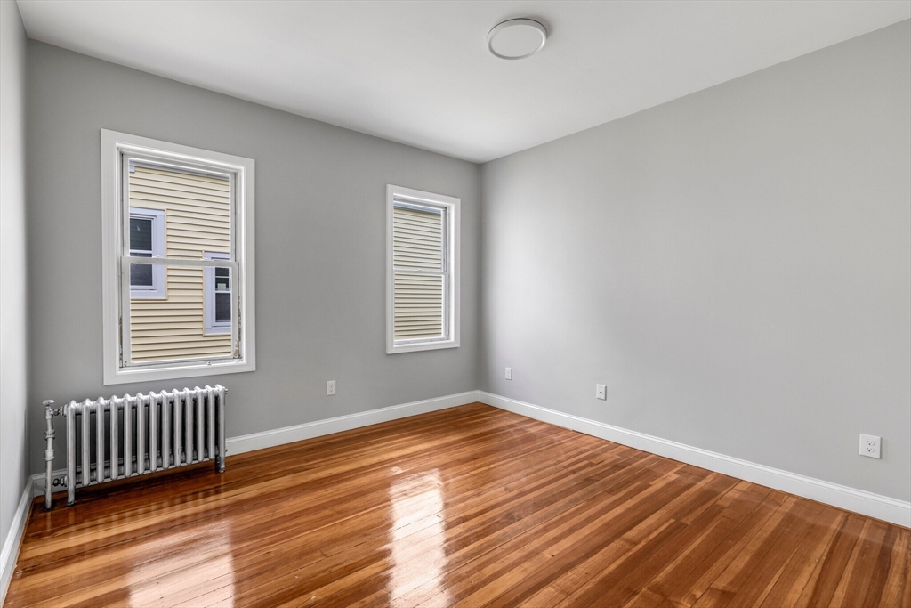 33 Wolcott Street, Unit 3 Boston, MA 02121 - Photo 5 of 8 an empty room with wooden floor and windows