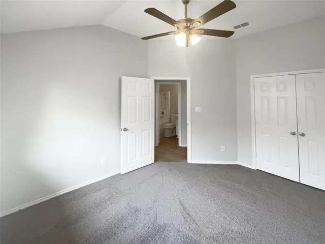 an empty room with closet and a ceiling fan