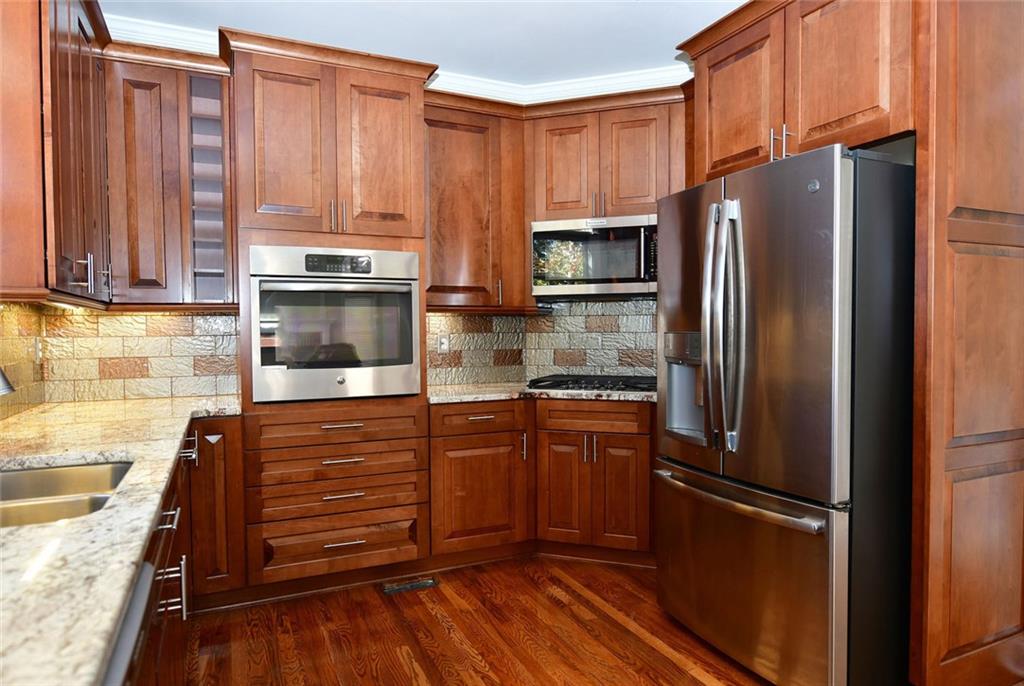 1767 Honey Tree Place Hoschton, GA 30548 - Photo 13 of 54 a kitchen with granite countertop wooden cabinets and stainless steel appliances