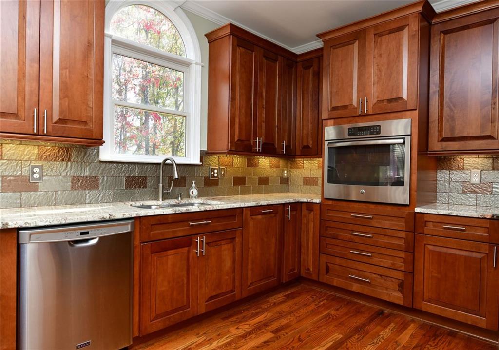 1767 Honey Tree Place Hoschton, GA 30548 - Photo 15 of 54 a kitchen with granite countertop wooden cabinets a sink and a window