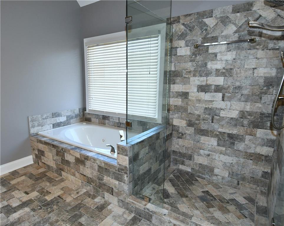 1767 Honey Tree Place Hoschton, GA 30548 - Photo 36 of 54 a bathroom with a bathtub and shower