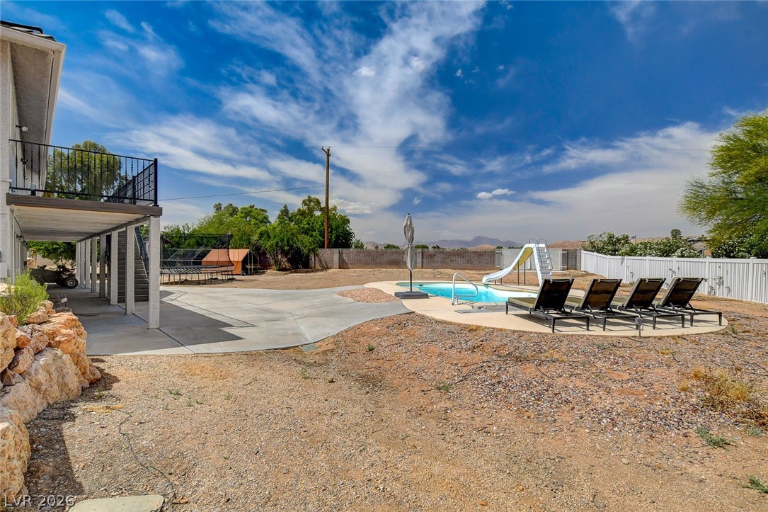 4362 Thistle Street Logandale, NV 89021 - Photo 76 of 99 An inviting backyard oasis offers a sparkling in-ground pool with a slide, complemented by a covered patio area.