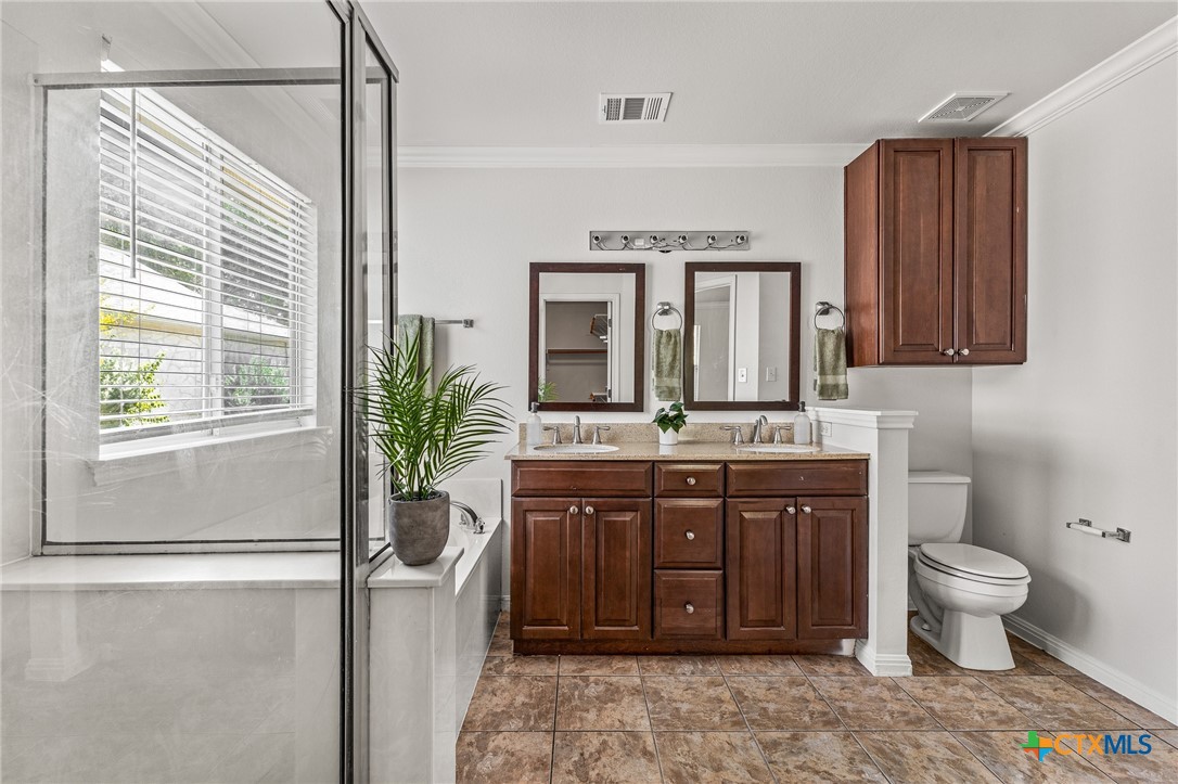 7733 Little Deer Trail Georgetown, TX 78628 - Photo 22 of 36 a spacious bathroom with a granite countertop sink a toilet and a mirror