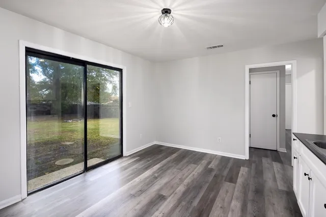 an empty room with wooden floor a ceiling fan and windows