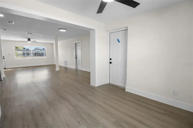 an empty room with wooden floor and windows
