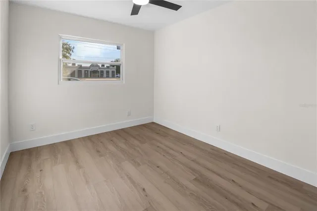 an empty room with wooden floor and window