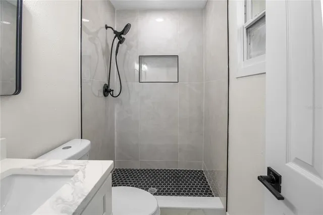 a bathroom with a granite countertop sink a toilet and shower