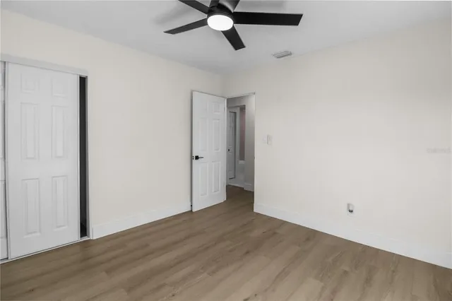 an empty room with wooden floor and ceiling fan