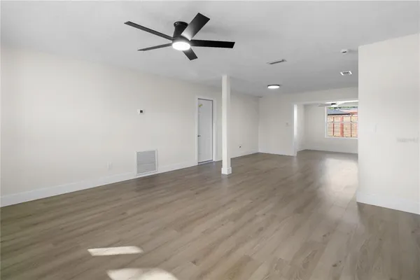 an empty room with wooden floor and a ceiling fan