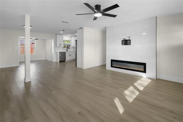 a view of a livingroom with a ceiling fan wooden floor and a ceiling fan