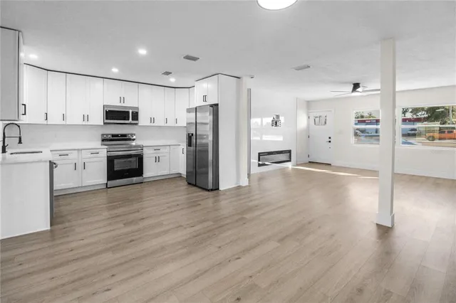 a kitchen with stainless steel appliances granite countertop a refrigerator stove top oven and cabinets with wooden floor