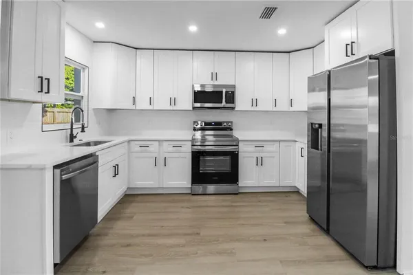 a kitchen with white cabinets stainless steel appliances and a sink