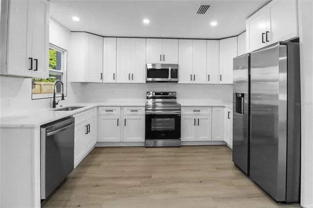 a kitchen with white cabinets stainless steel appliances and a sink