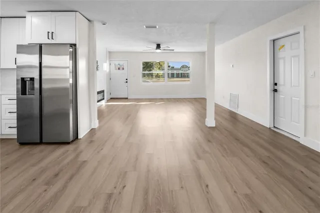 a view of a kitchen with wooden floor refrigerator and window