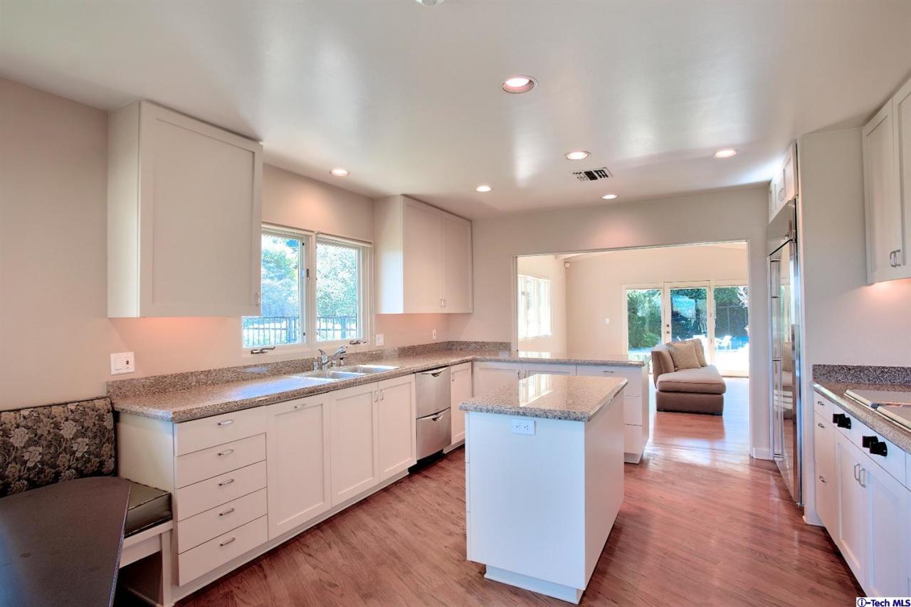 1114 Heatherside Road Pasadena, CA 91105 - Photo 13 of 35 a large kitchen with stainless steel appliances a large counter top a sink a window and white cabinets