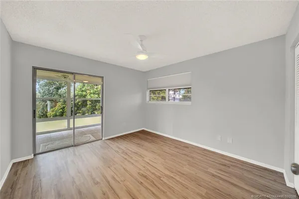 a view of empty room with wooden floor and fan