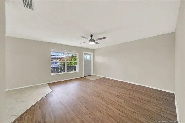 a view of an empty room with wooden floor and a window
