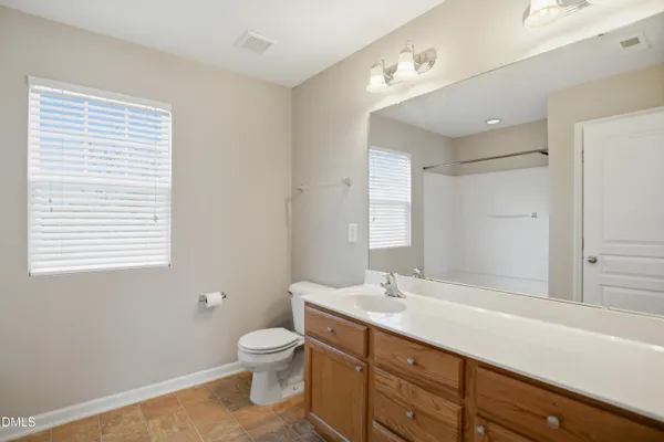 a bathroom with a granite countertop sink toilet a large mirror and a bathtub